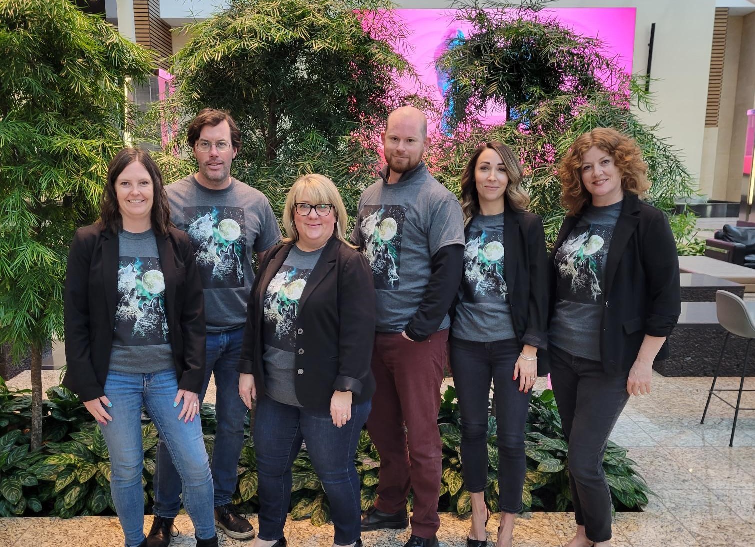 The Land Department team posing together wearing matching tee shirts of a wolf howling at the moon