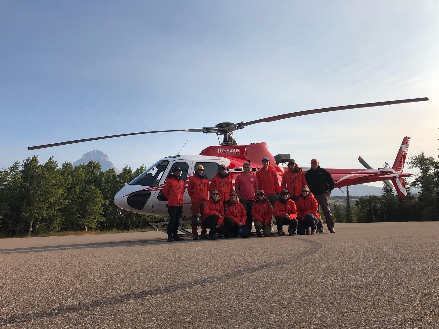 Southwest Alberta Regional Search and Rescue volunteers post in front of a red helicopter 